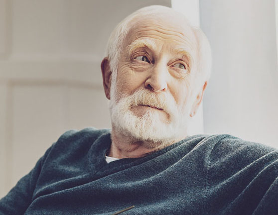 Hombre adulto tranquilo sentado mientras por la ventana 