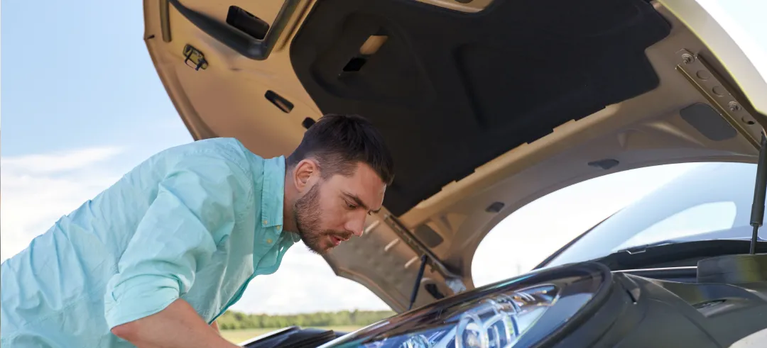 Hombre con el capó subido mirando si existe algún problema en el interior del coche