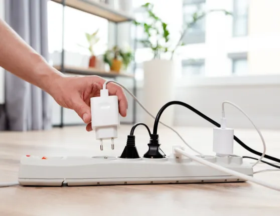 Persona enchufando un cargador en una regleta llena de cables